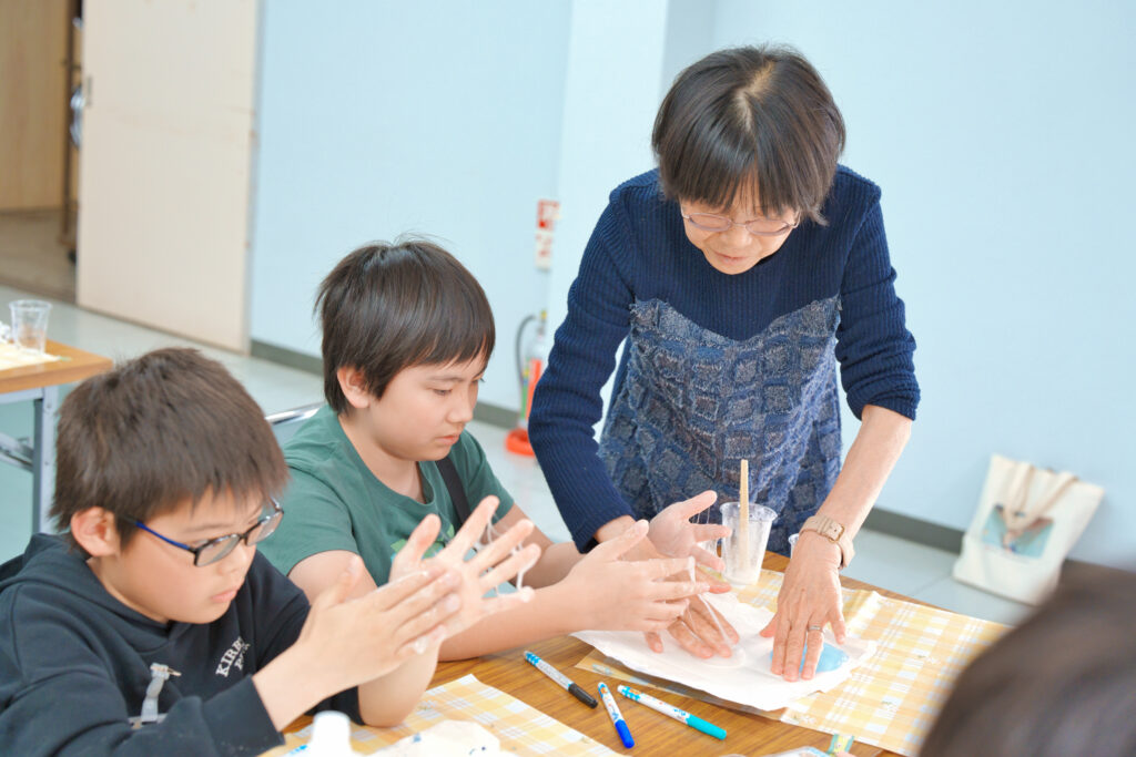 ふわふわスライムに色を付けている先生と子どもたち