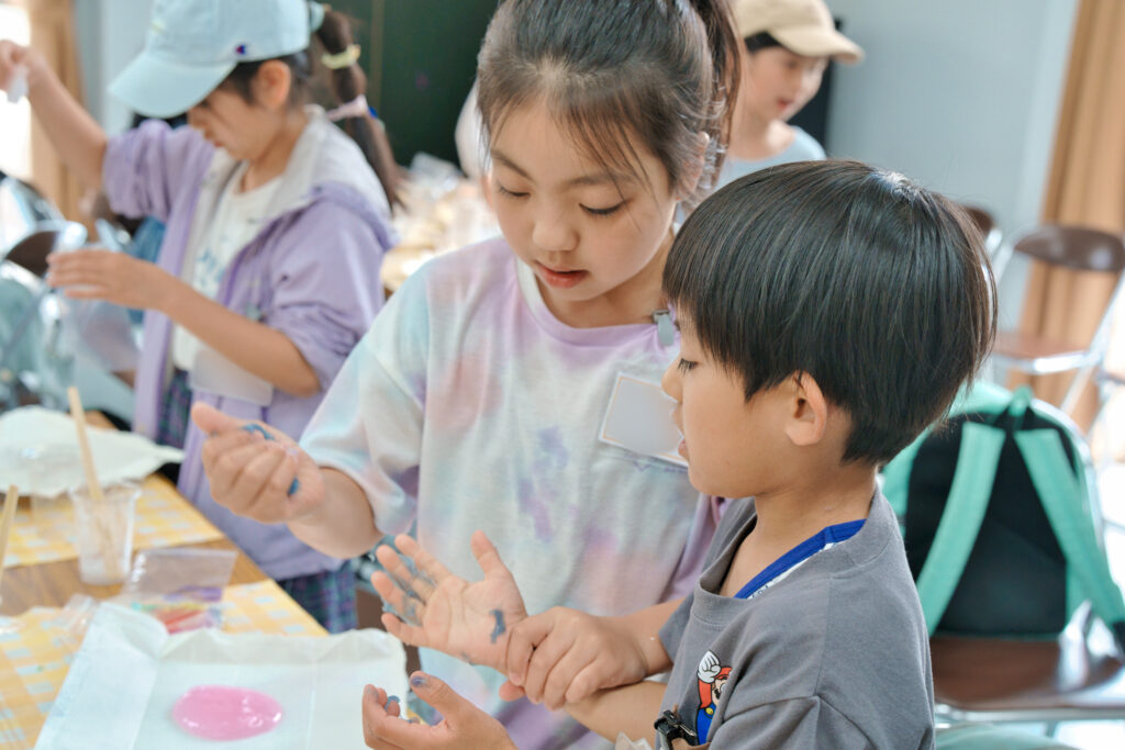 協力してスライムに色を付けている子どもたち