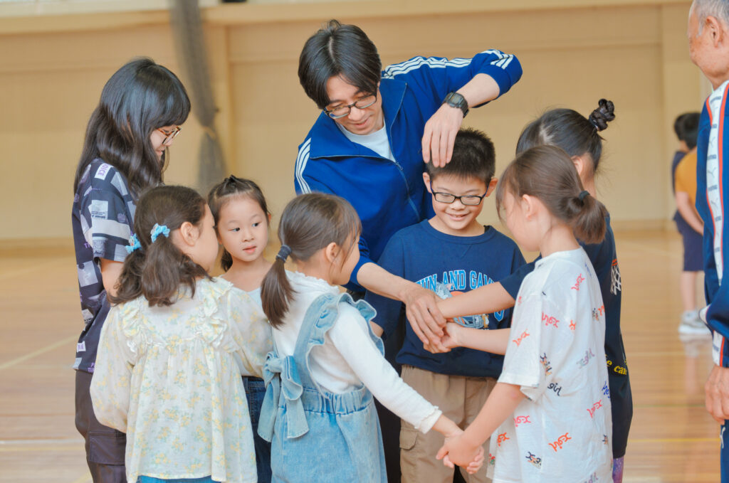 輪になり手をつなぐ子どもたちと、教えるいっぺいちゃん