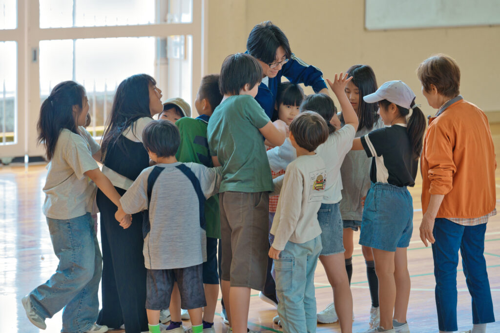 手を繋いだまま円に戻ろうとするたくさんの子どもたち