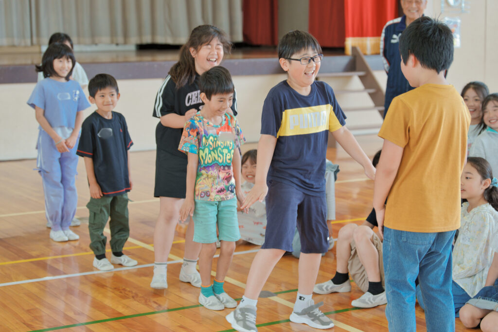 ジェスチャーで後ろの人に伝えようとする子どもたち
