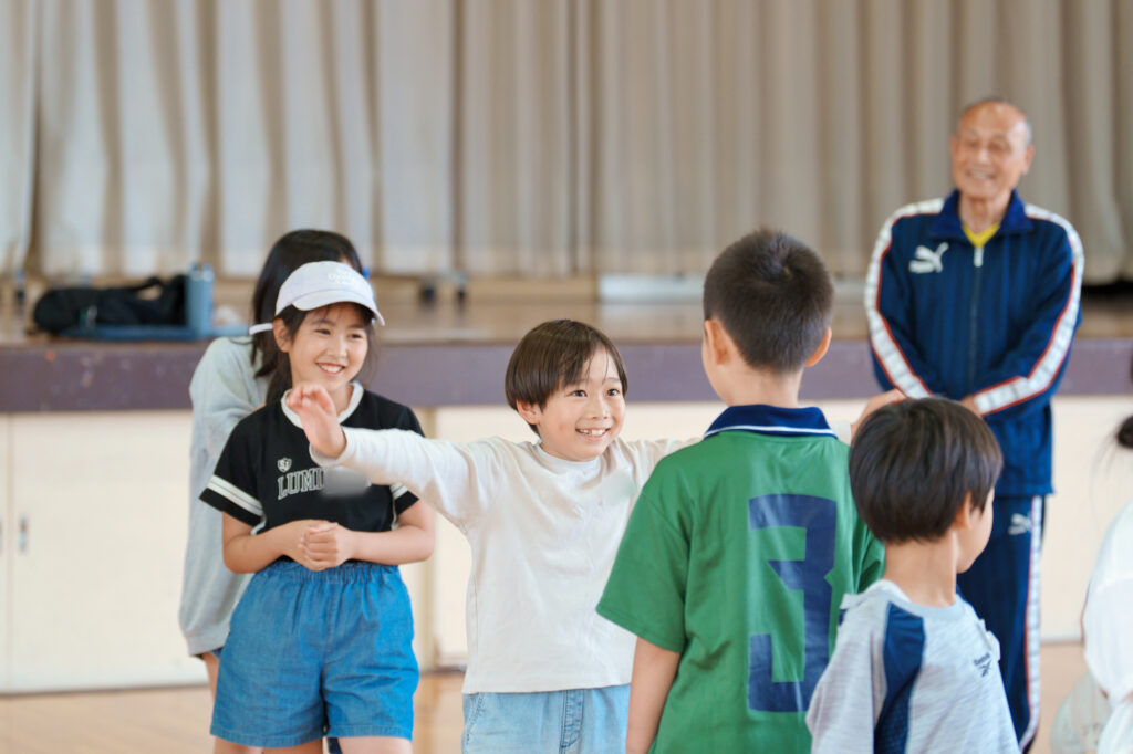 ジェスチャーで後ろの人に伝えようとする子ども