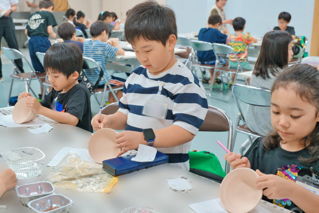 器に鉛筆で下書きをする子どもたち