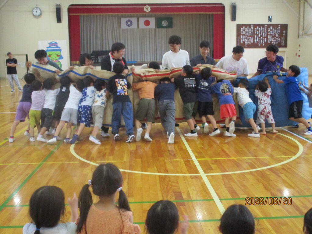 子どもたちがクッションを挟んだ保護者達と押し合っている