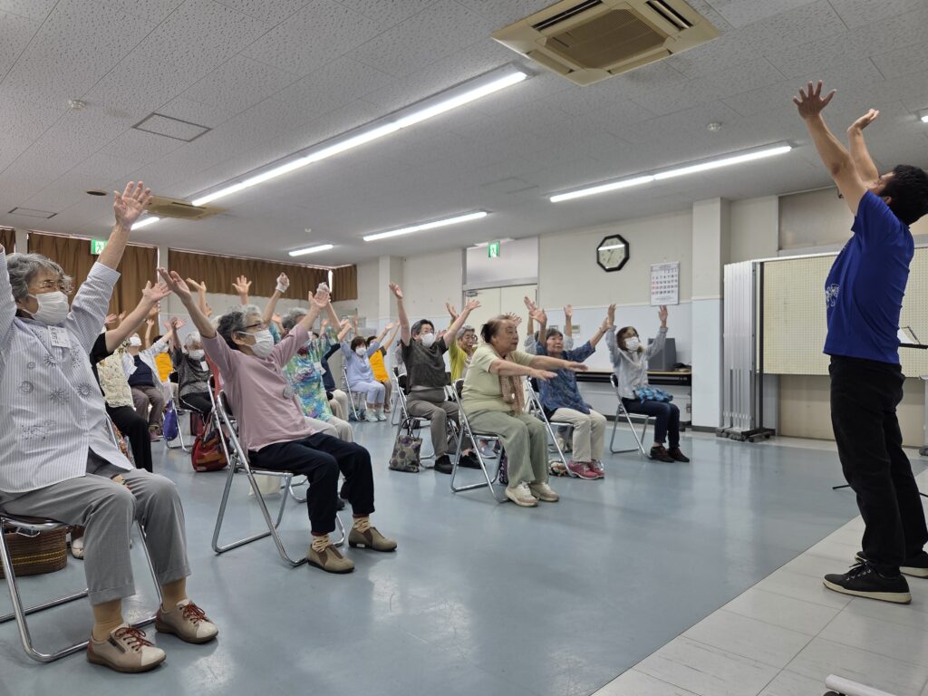 塚本先生と会員たちが両手を上に掲げている