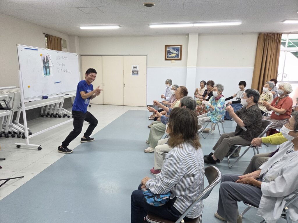 指を立てている塚本先生と会員たち