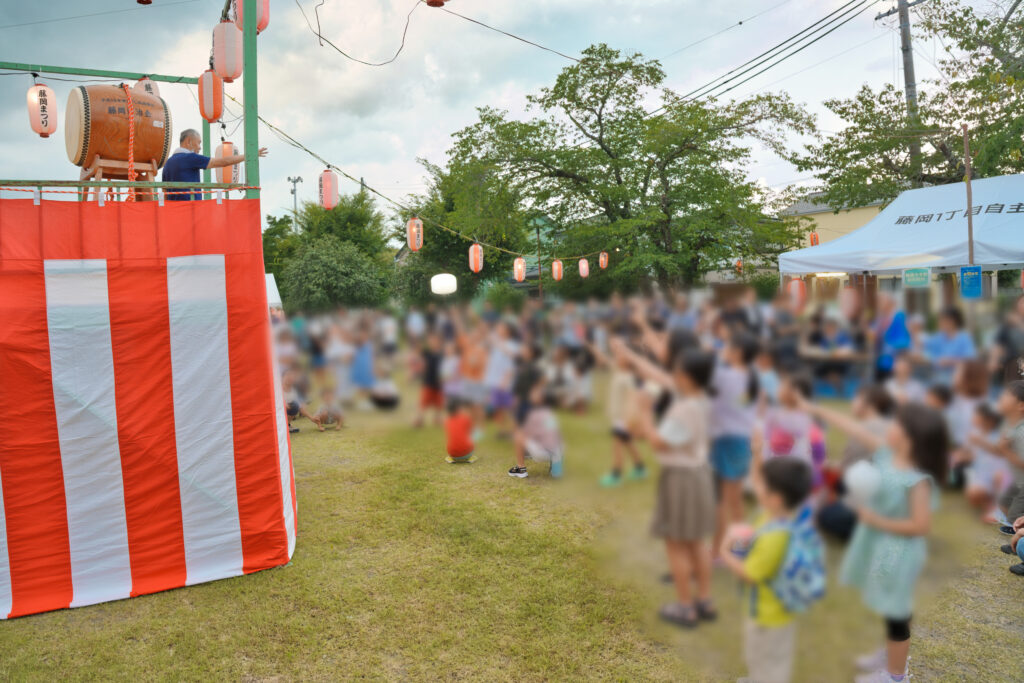 やぐらの上のまつり委員長とじゃんけんをする、小学生以下の子ども達