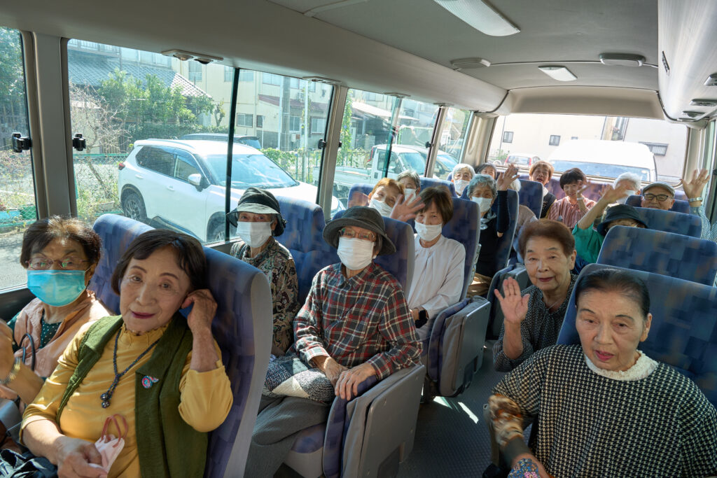 多くの会員の皆様が乗るバスで、カメラへ笑いかける皆様